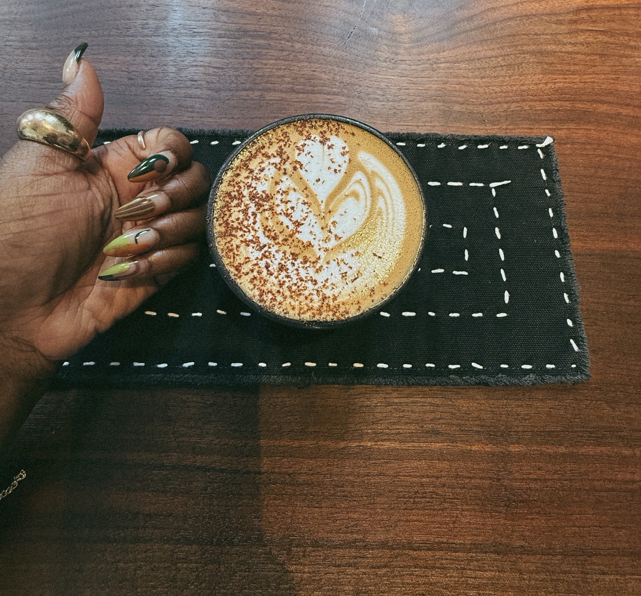 A latte with latte art on a black stitched placemat